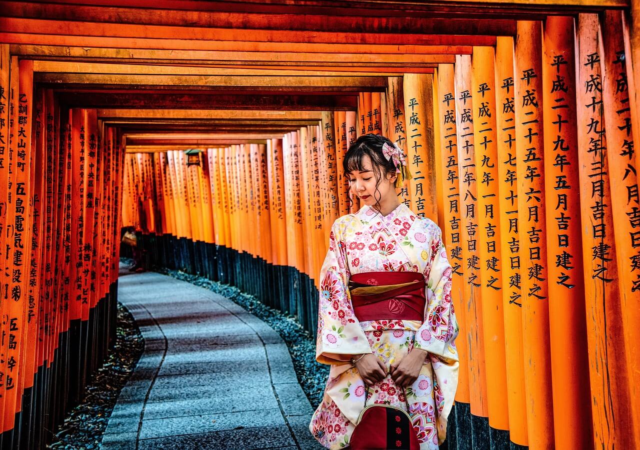 Tunel czerwonych bram torii Fushimi Inari w Kioto – kobieta w kimonie w tradycyjnym sanktuarium shintō w Japonii