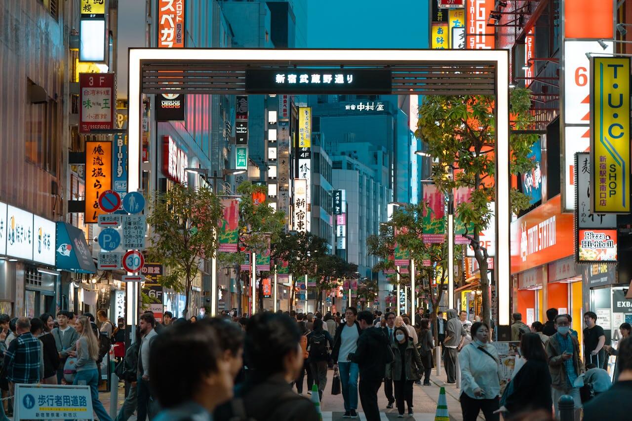 Wejście na ulicę Shinjuku z neonami i tłumem przechodniów