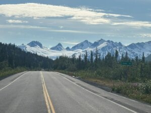 Droga prowadząca do Valdez w stanie Alaska, otoczona lasem i z widokiem na ośnieżone szczyty i lodowiec